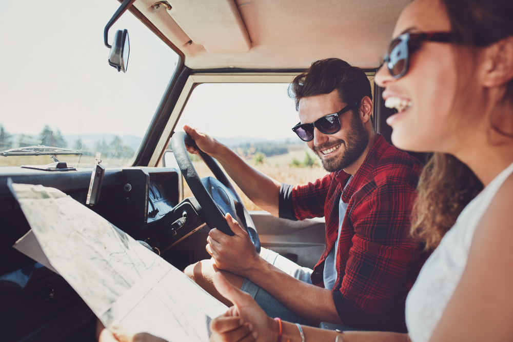 Happy young couple with a map in the car. 