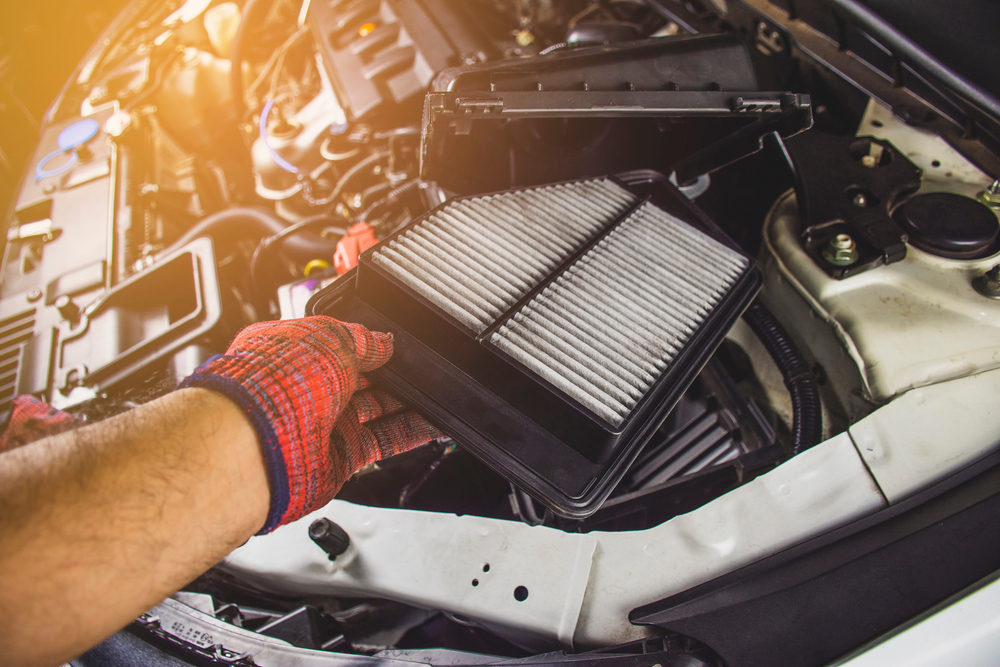 mechanic removing dirty air filter from car