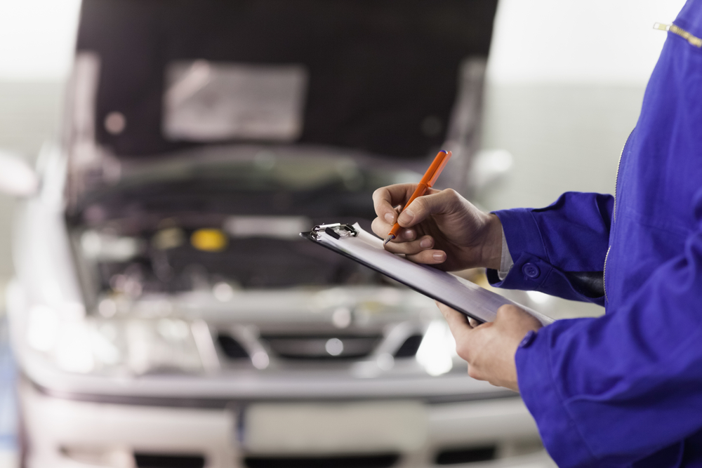 Closeup of a man writing on a clipboard in a garage