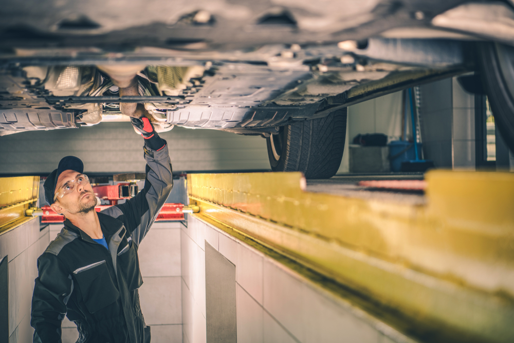 Auto Service Worker Checking Car Under Carriage Looking For Potential Issues.