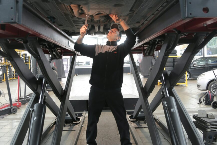 an in Black Jacket and Black Pants Standing Under Vehicle