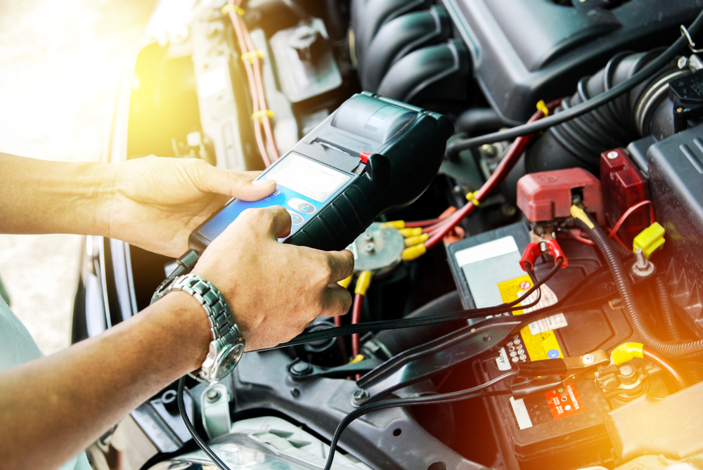 mechanic holds handheld tuner over car's engine