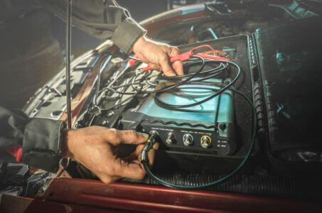 technician connecting diagnostic equipment to a vehicle’s electrical system