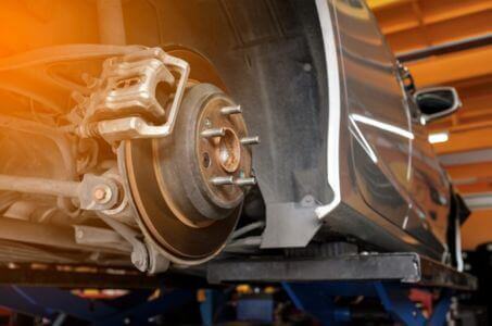 exposed brake rotor and caliper during a brake inspection on a lifted vehicle