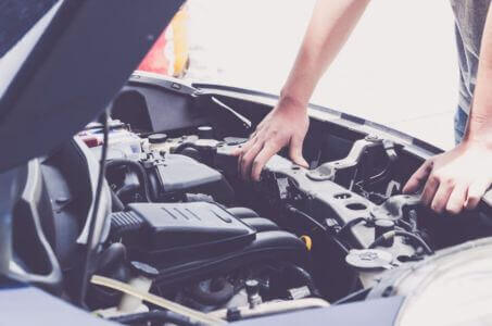 technician inspecting engine components under the hood during a diagnostic check