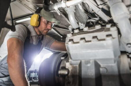 diesel mechanic inspecting fuel system components under a heavy-duty vehicle