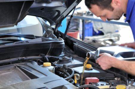 technician pouring engine oil during a routine vehicle maintenance service