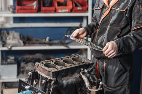 mechanic inspecting an engine block and head gasket during repair