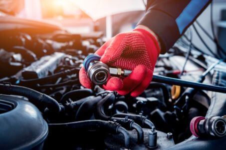 technician testing radiator components under the hood of a vehicle