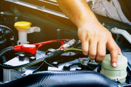 checking fluid levels under the hood during routine vehicle maintenance