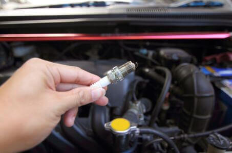 hand holding a spark plug during a vehicle tune-up inspection
