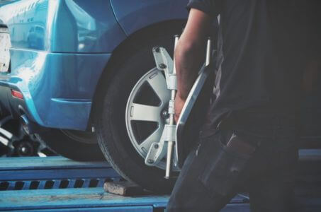 technician adjusting wheel alignment equipment on a vehicle in the shop