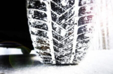 winter tire tread gripping snow on an icy road surface