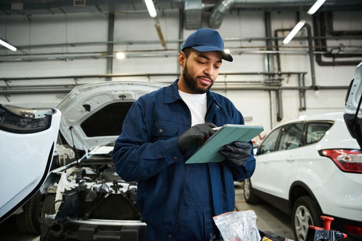 Auto technician using a tablet in a vehicle repair garage