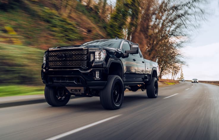 Black heavy-duty pickup truck driving on a rural highway