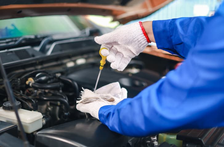 Mechanic checking engine oil level with a dipstick during vehicle maintenance