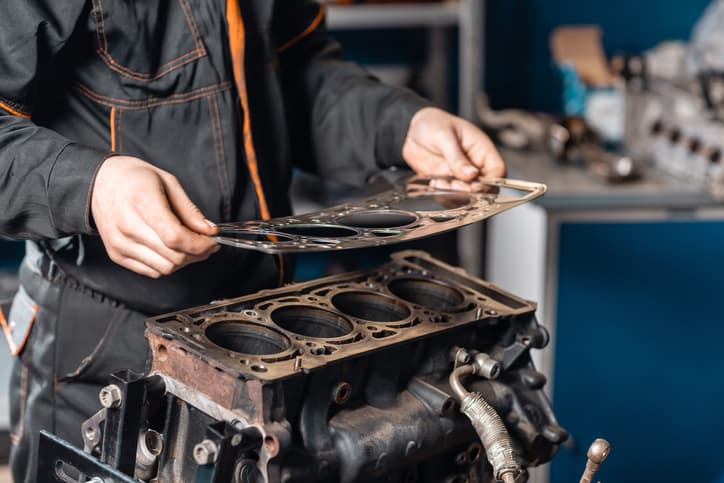 Mechanic installing a head gasket on an engine block during repair