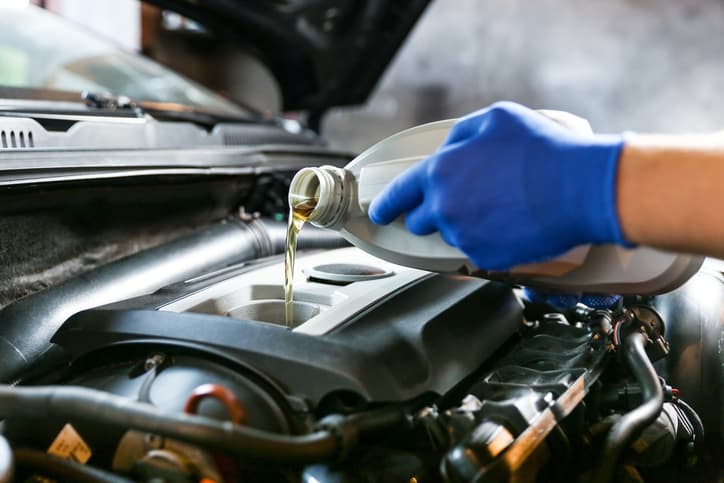 Mechanic pouring engine oil into a car engine during vehicle maintenance
