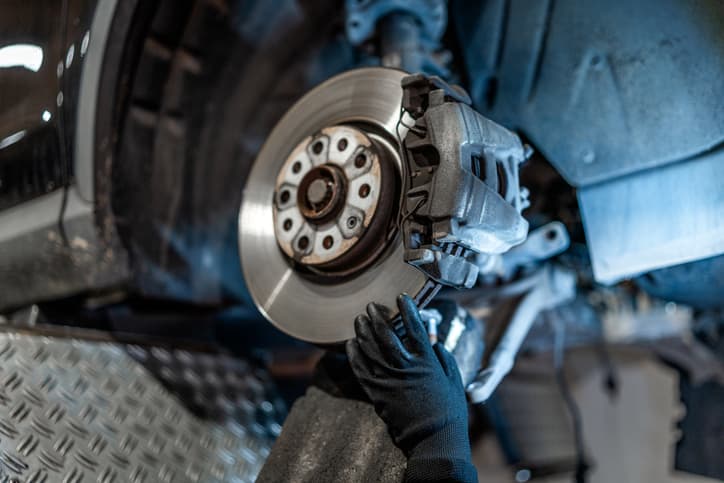 Mechanic inspecting or repairing a vehicle brake rotor and caliper