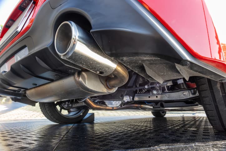 Underside view of a red vehicle showing the exhaust system and muffler