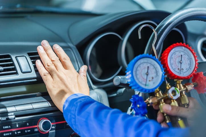 Technician checking car air conditioning performance with AC pressure gauges
