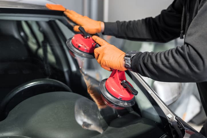 Technician repairing or replacing a cracked car windshield using suction tools