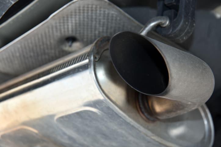 Close-up of a vehicle exhaust pipe and muffler underneath a car