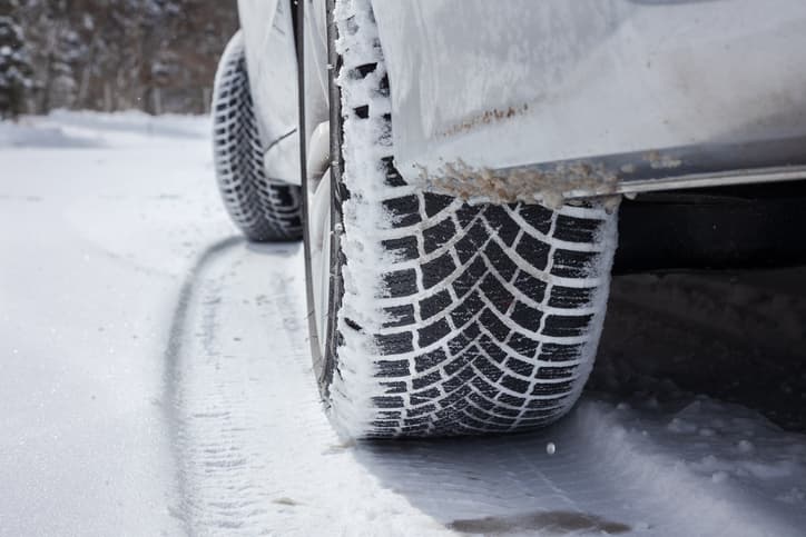 Close-up of a winter tire driving on a snow-covered road